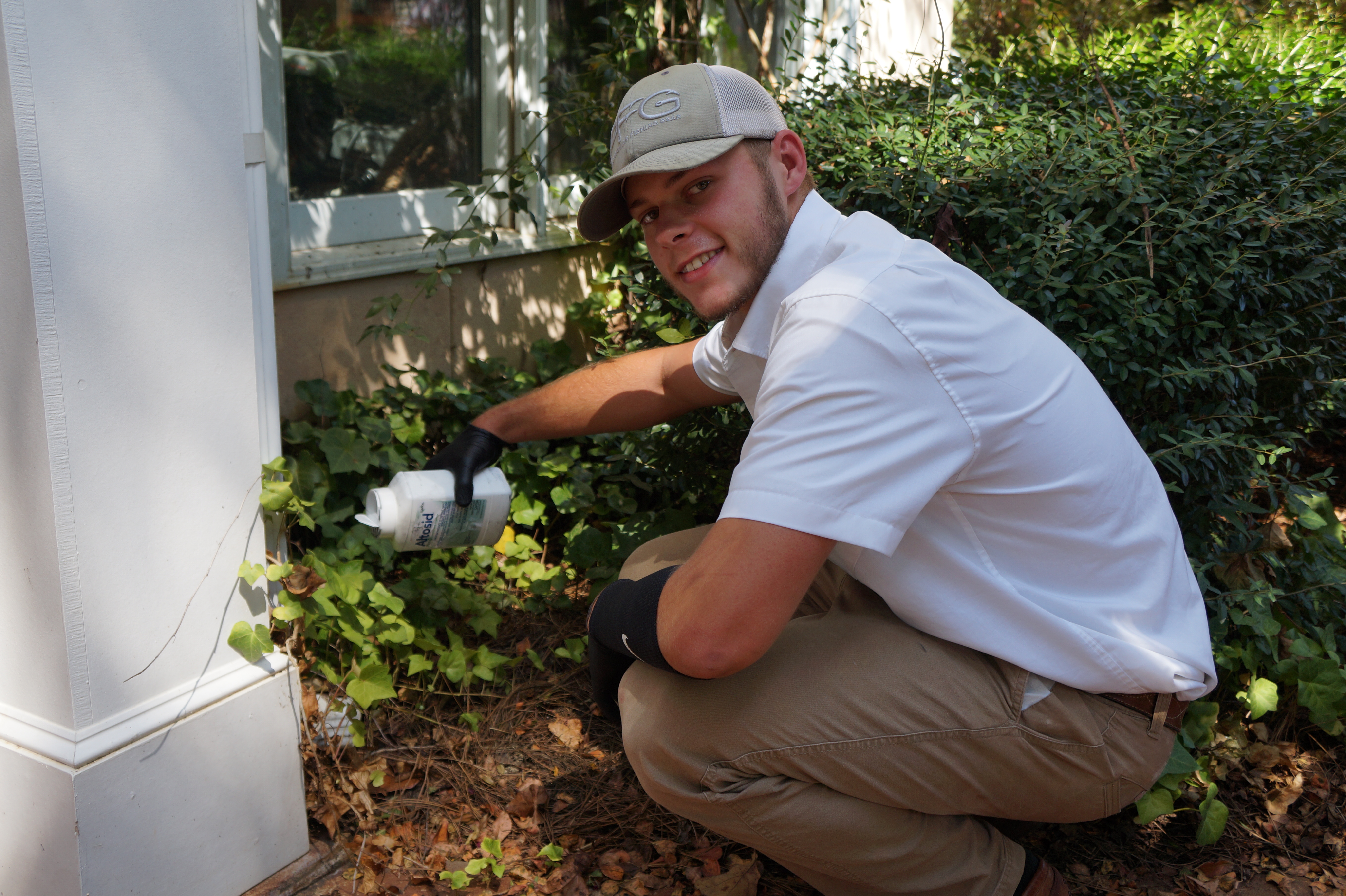 Pest control technician treating foundation of home for bugs